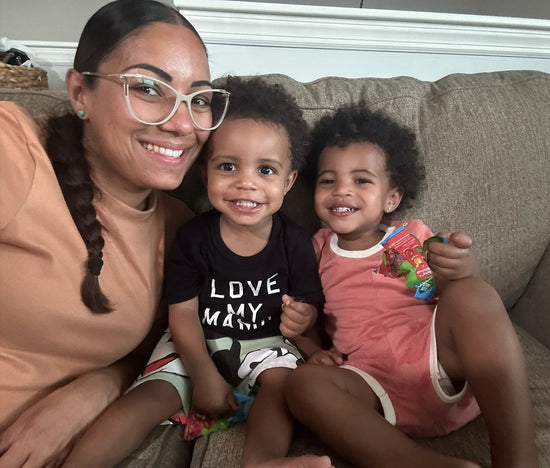Woman with two children sitting on a couch, smiling at the camera.